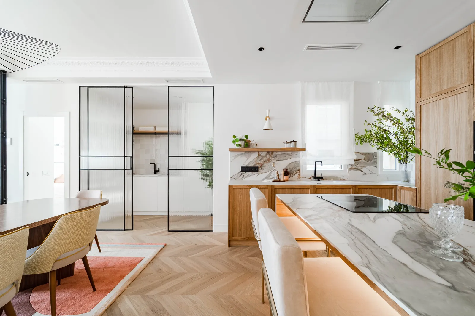 Cocina abierta con cristalera negra y mármol en una reforma integral en Recoletos, Madrid